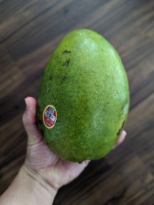 Small produce shop inside selling gigantic mango.