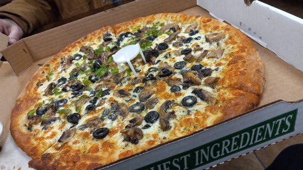 A white pizza with mushrooms and olives and half with green peppers