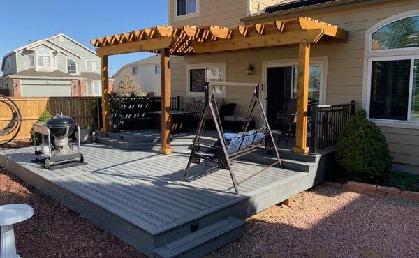 Wood pergola provides shade over part of ground level composite deck.