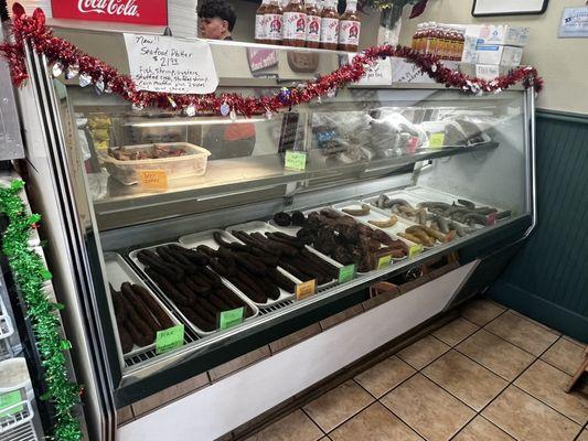 Counter full of smoked treats and sausages.