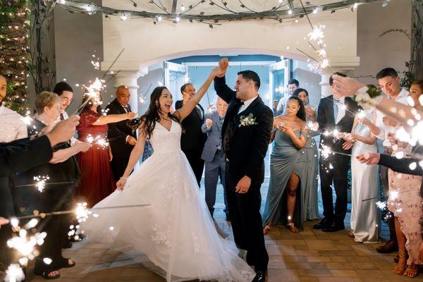 Capture the magic as the bride and groom exit under a stunning gazebo, surrounded by sparkling lights and joyful guests with sparklers!