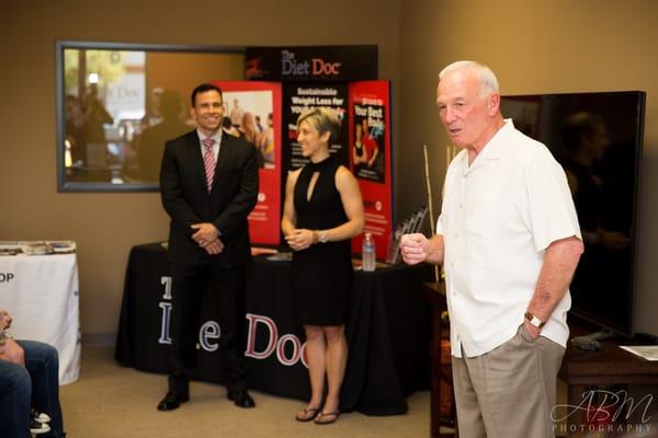 Dr. Joe Klemczewski, founder of The Diet Doc, LLC, & Kori Propst, Vice President and Wellness Director, watch as Jerry Sanders speaks.