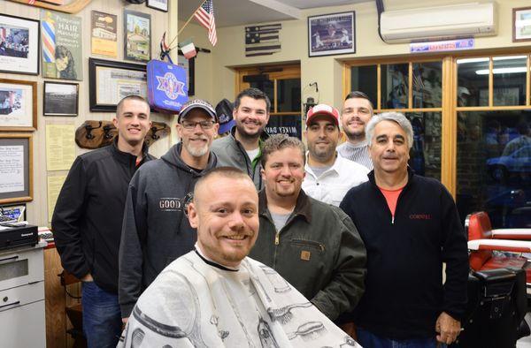 A groom getting his haircut and his groomsmen who will follow.