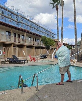 The pool boy aka my husband skimming the pool debris before going in for a dip.