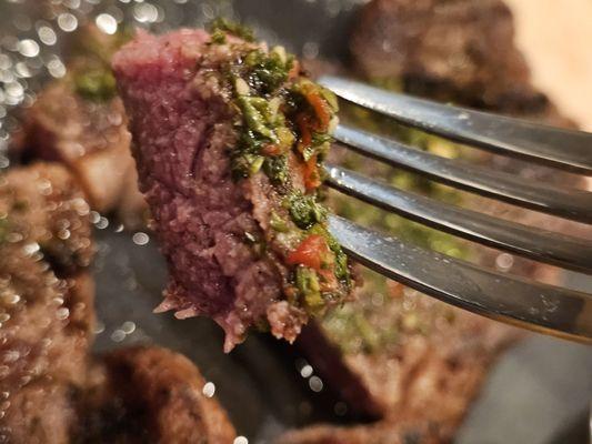 Close-up of a fork holding a piece of the steak.