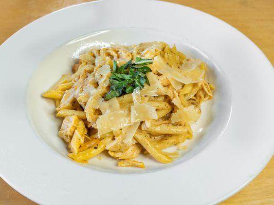 Chicken alfredo has penne pasta tossed in garlic cream sauce, grated parmesan and basil