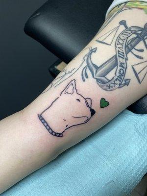 my new tattoo of a line drawing of a pitbull mix dog, with a spiked collar, and small green heart next to it.