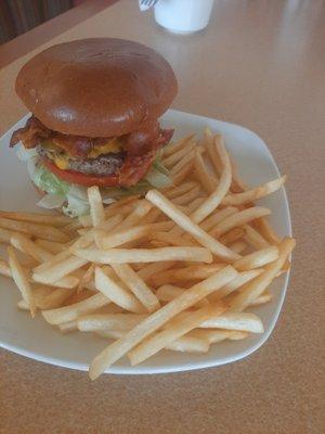 Bangin' burger - Server on a brioche bun with lettuce, tomato, bacon, and a fried onion ring on top.