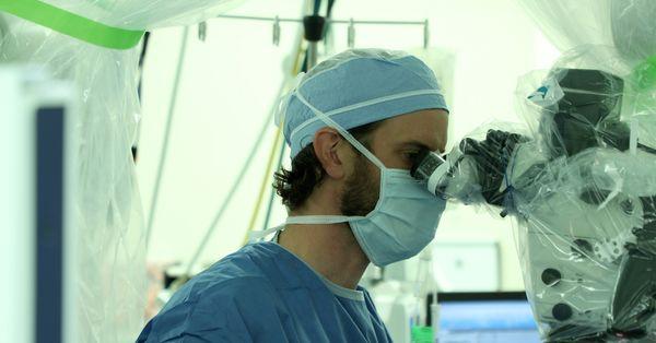 Dr. Mahoney in the OR performing a spine surgery with a tiny camera and instruments ensuring a  minimally invasive surgery is performed.