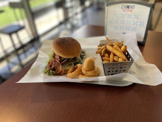 burger with fried egg on top with tomato lettuce onions seasoned French fries and onion rings and with a fountain drink