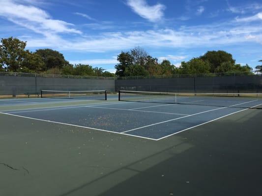 Two tennis courts surrounded by a fence