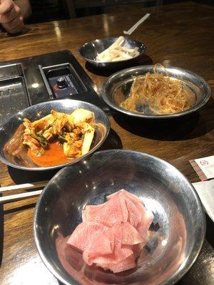 Side dishes. Front to back: radish, kimchi, noodles, not sure