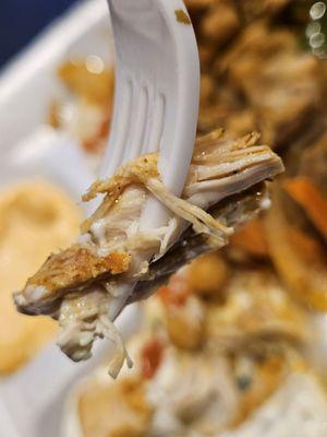 A close-up of a fork holding a piece of ghe Chicken from the Chicken Shawerma Platter.