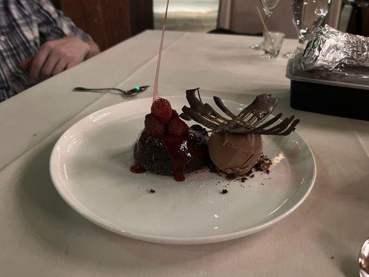 Molten lava cake with raspberry sauce, chocolate ice cream and candied raspberries