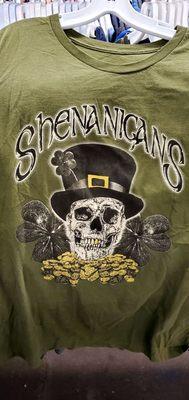 Shirt says, "Shenanigans". Has a skull w/ top hat, clovers, and gold coins!