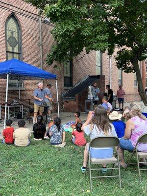 Children and adults watching a performer at an outdoor party