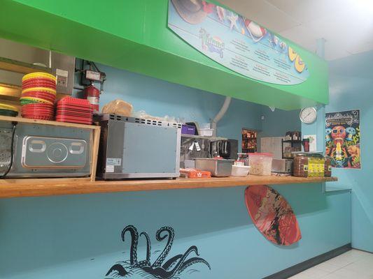 The ordering counter currently filled with microwaves toasters scales uncooked food and giant jars of peppers Etc