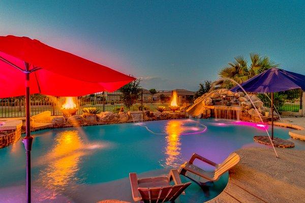 Pool with grotto slide, baja seat, and water features.