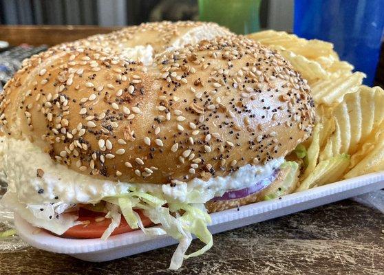 Chicken salad with lettuce, tomato and onion on a toasted everything bagel. Giant and delicious sandwich.