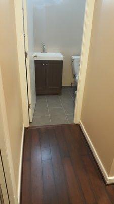 Bath floor complete, adjacent to laminate floor in hallway.