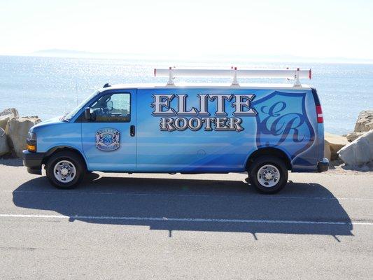 Elite Rooter service van parked by the ocean, showcasing the company's professional branding against a scenic backdrop