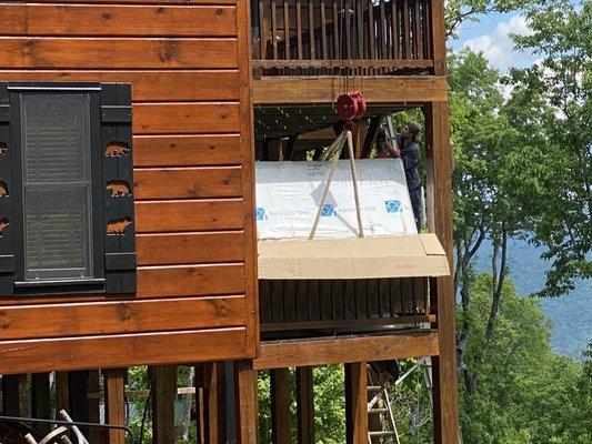 The hot tub being placed on the back porch