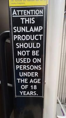 Warning sign posted on tanning bed