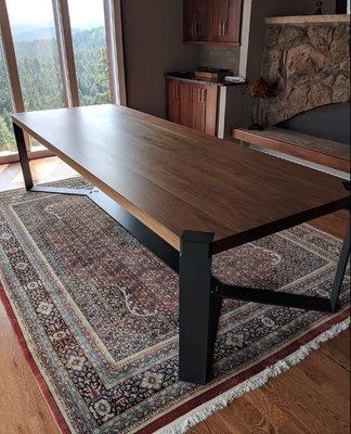 Custom built walnut dining table with blackened flat strap steel base.