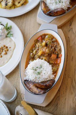 Classic Ropa Vieja stew served with carmalized plantains white rice black beans