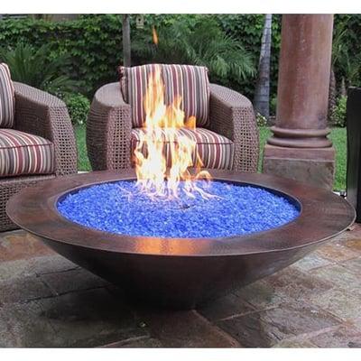 This is a gas fire pit with a copper base with blue glass