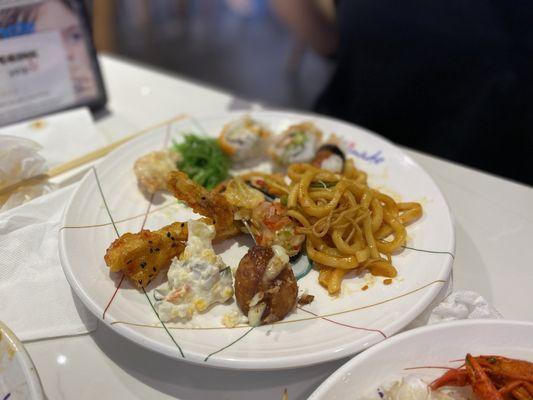 Chicken wings, spicy udon stir fry, corn salad, and sushi rolls.