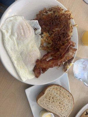 Eggs over easy with hash bacon and toast