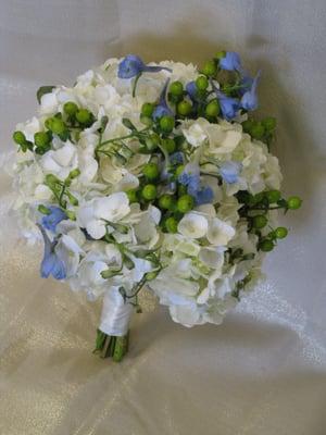 Mix of hydrangea, blue delphinium, and green hypericum berries