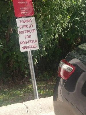 These signs are the only deterrent to keep cars from parking here, Holiday Inn's management staff neglects these spaces Tesla owns.