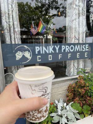 Coffee held in a hand outside the coffee shop