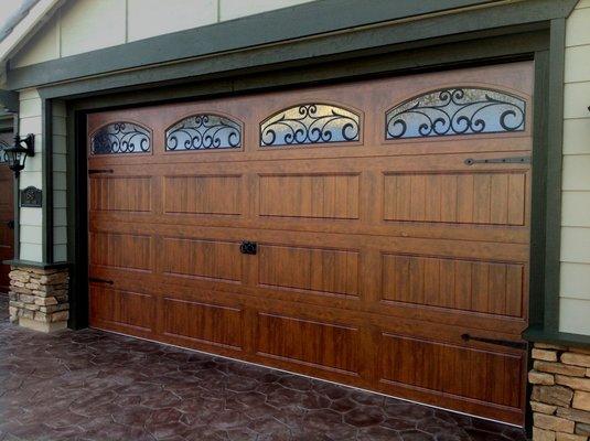 Steel garage door with walnut wood grain finish, wrought iron arched windows and decorative hardware (handles & hinges)