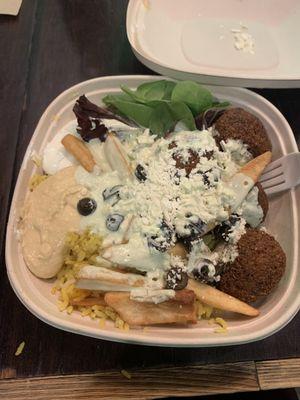 Bowl with rice, fries, falafel, tzatziki, black olives, hummus, mixed greens, and feta cheese