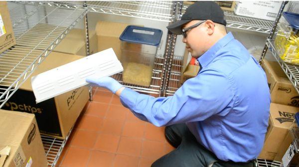 Technician checking a trap in a commercial facility for pest activity.