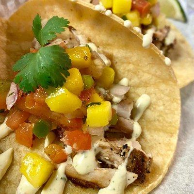 El Dorado Tacos made with grilled mahi-mahi, lime-cilantro crema & mango pico salsa served on a GF corn tortilla