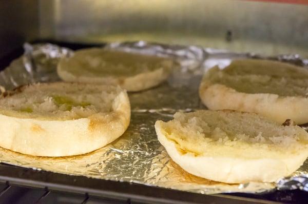 English muffins toasting with a touch of garlic infused olive oil brushed on