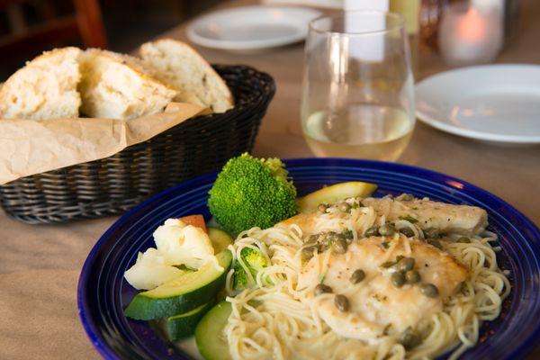 Homemade chine piccata - perfectly sautéed chicken breasts served with a white wine, butter, lemon sauce topped topped with capers.