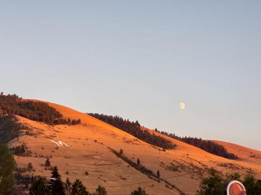 The view of the M behind the university with a moon rising.