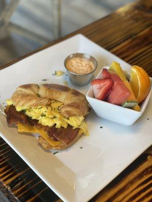 Breakfast Sandwich on a croissant with fresh fruits