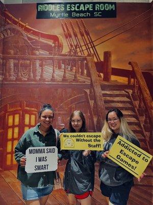 Three people who completed an escape room, holding signs.