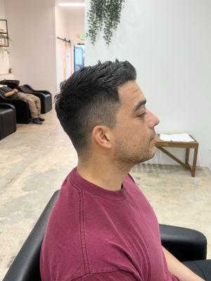 Classic men's fade haircut with a clean taper on the sides and a textured, neatly styled top by Yuna