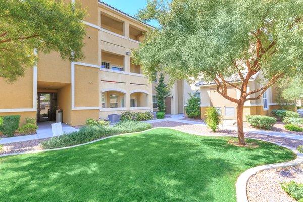 Community lawn with green grass and zero landscaping and view of balconies.