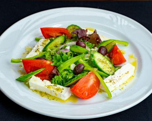 Greek Salad with locally grown tomatoes, Fresh Organic Greens, Cucumber, Kalamata Olives, Feta Imported from Greece, and house made dressing