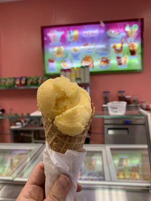 Single scoop mango ice cream in waffle cone