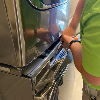 Technician in action on stacked washer/dryer unit.