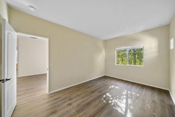 Large bedroom with wood style plank flooring, modern finishes, spotlight lighting and breathtaking views of greenery.